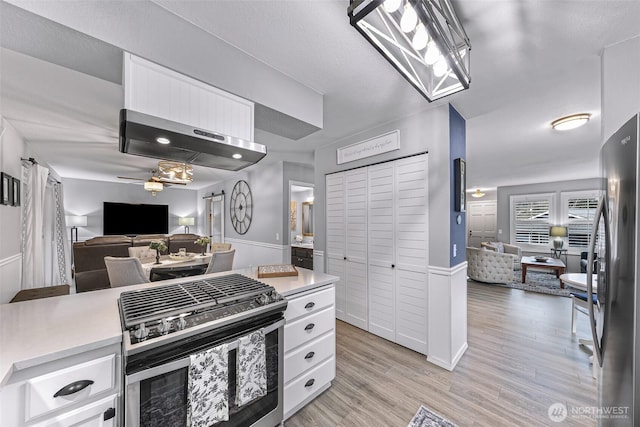 kitchen with open floor plan, appliances with stainless steel finishes, white cabinetry, and light countertops