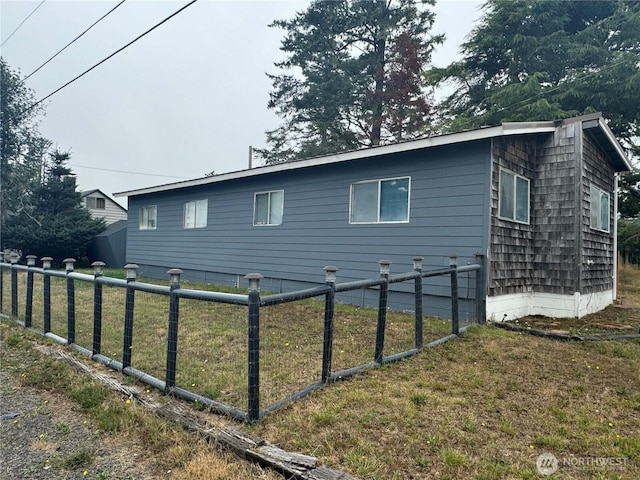 view of side of property featuring a lawn and fence