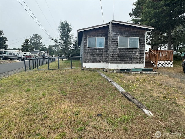 view of property exterior with a lawn, fence, and a wooden deck