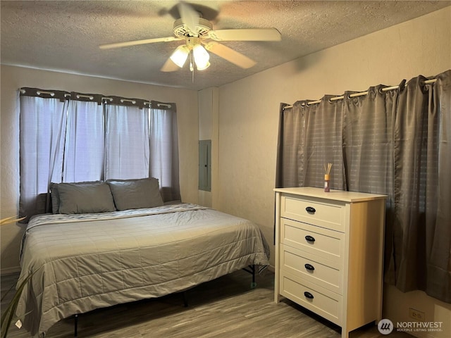 bedroom with electric panel, a textured ceiling, ceiling fan, and wood finished floors