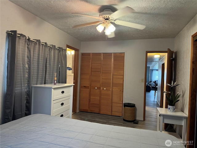 bedroom with a closet, a textured ceiling, wood finished floors, and a ceiling fan