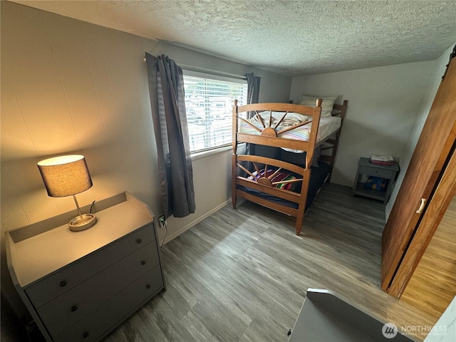 bedroom featuring a textured ceiling, baseboards, and wood finished floors