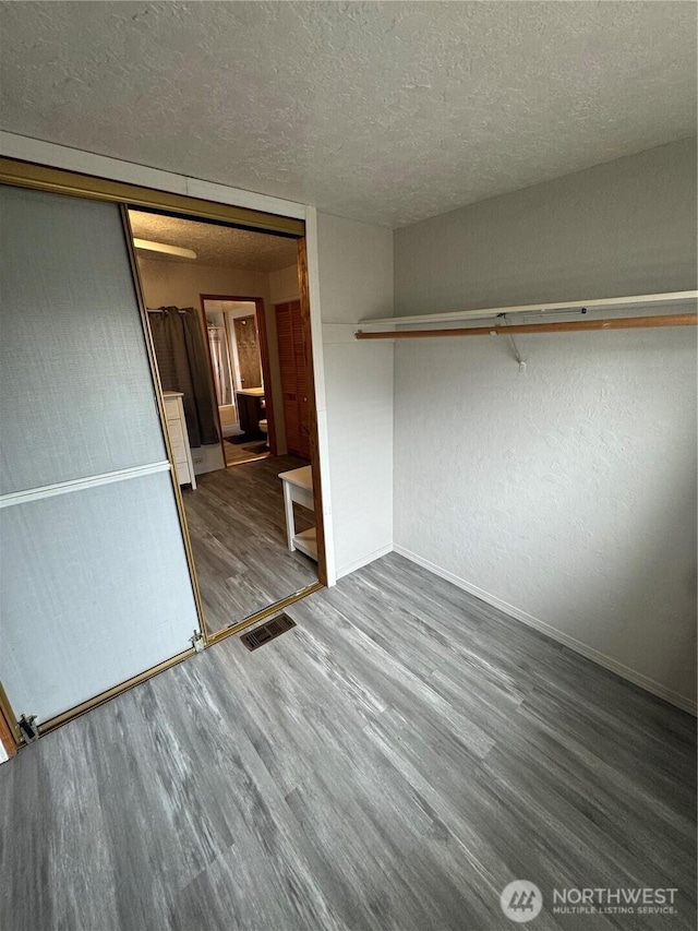 interior space featuring wood finished floors, visible vents, a closet, and a textured ceiling