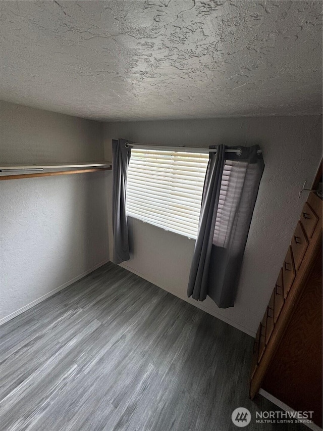 unfurnished bedroom with a textured ceiling and wood finished floors