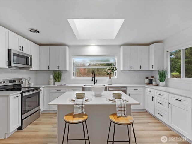 kitchen featuring a breakfast bar area, plenty of natural light, appliances with stainless steel finishes, and a sink