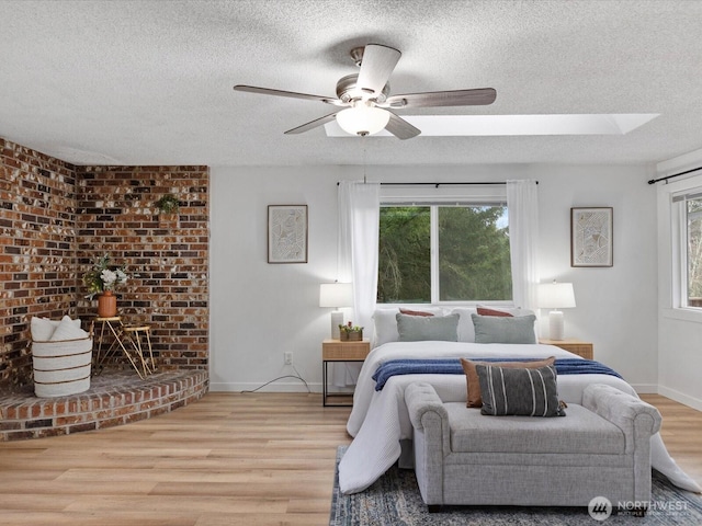 bedroom featuring light wood-style flooring, multiple windows, a ceiling fan, and a textured ceiling