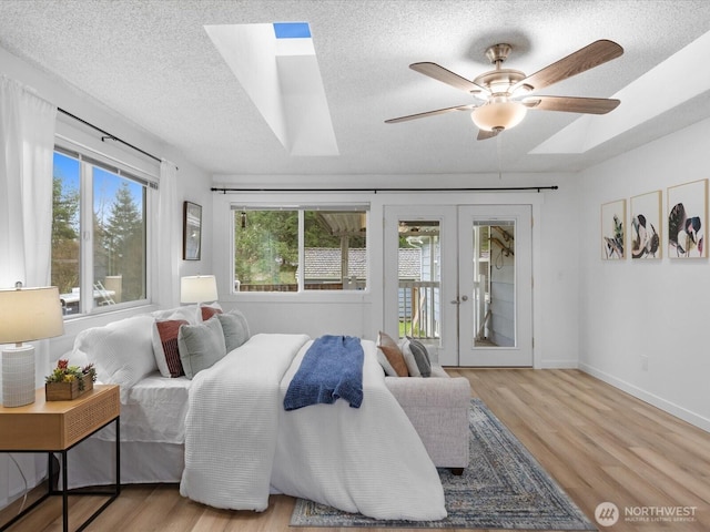 bedroom featuring wood finished floors, baseboards, french doors, a textured ceiling, and access to outside