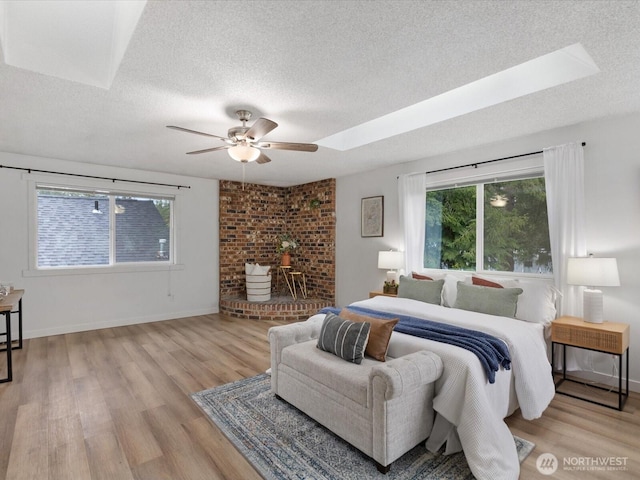 bedroom with baseboards, a textured ceiling, and light wood-style flooring