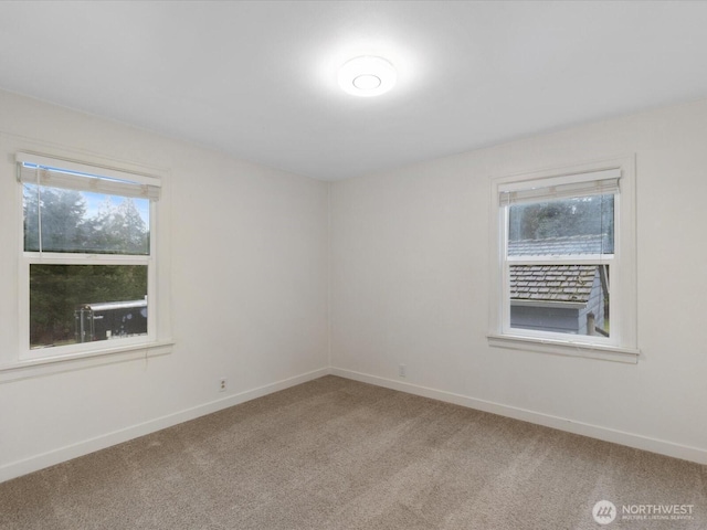 unfurnished room featuring baseboards, light carpet, and plenty of natural light