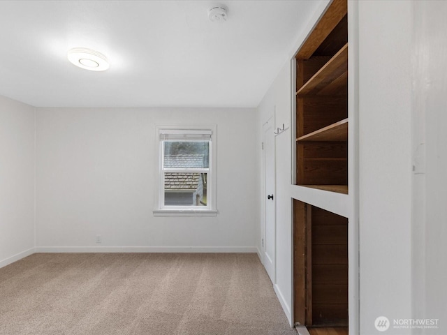 carpeted empty room featuring baseboards