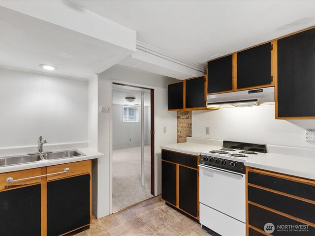 kitchen featuring electric range, light carpet, under cabinet range hood, a sink, and light countertops