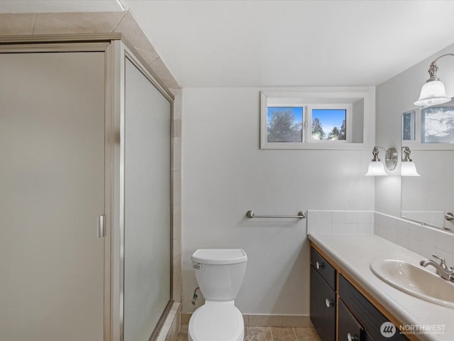 bathroom featuring vanity, a shower stall, and toilet