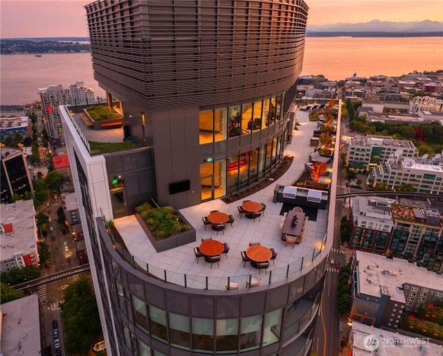 balcony at dusk featuring a patio and a water view