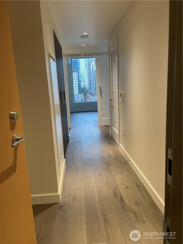 corridor featuring baseboards and wood-type flooring