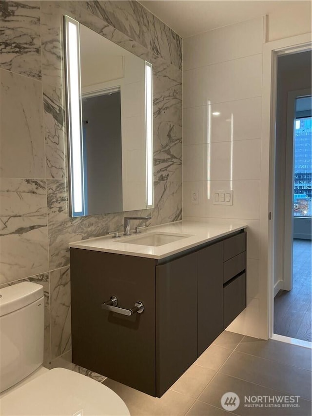 bathroom with toilet, tile walls, and vanity