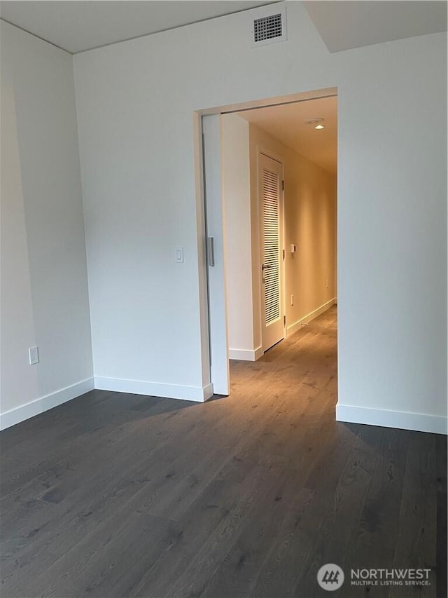 spare room with dark wood finished floors, baseboards, and visible vents