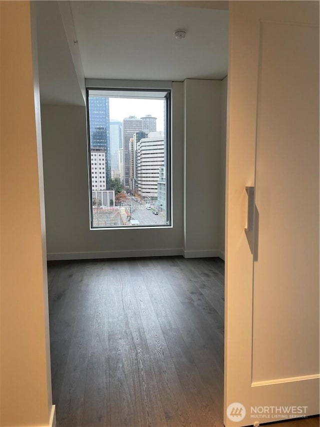 empty room featuring baseboards, a view of city, and wood finished floors