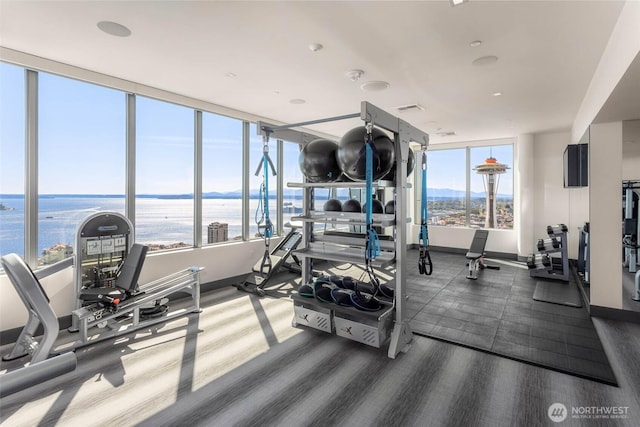 exercise room featuring visible vents, baseboards, and a water view