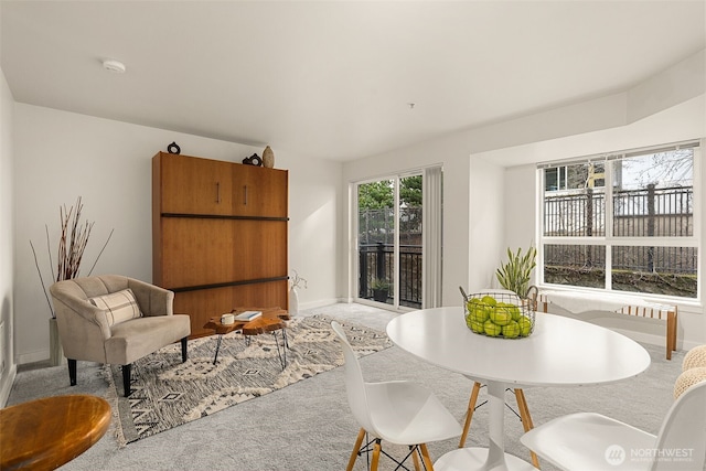 dining area featuring baseboards and light carpet