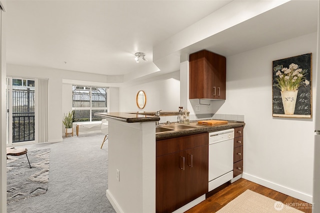 kitchen with baseboards, a peninsula, a sink, dishwasher, and dark countertops