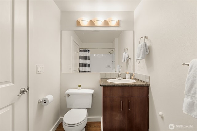 bathroom featuring a shower with curtain, toilet, wood finished floors, baseboards, and vanity