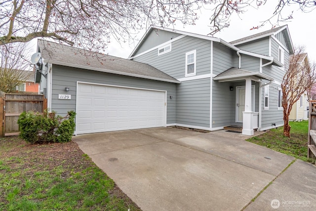 traditional-style house featuring concrete driveway, roof with shingles, a garage, and fence