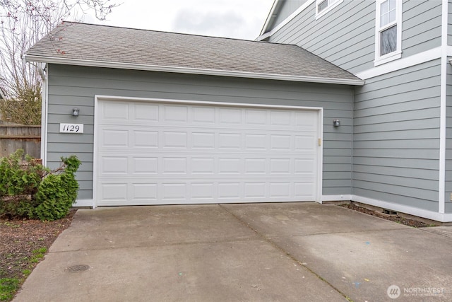 garage featuring driveway and fence