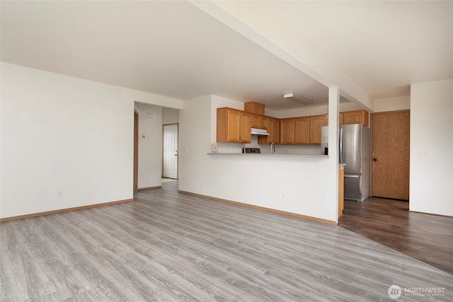 unfurnished living room featuring wood finished floors and baseboards