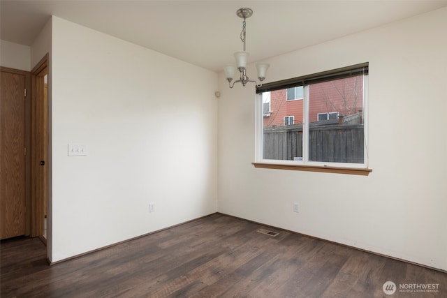 empty room featuring visible vents, dark wood-type flooring, and a notable chandelier