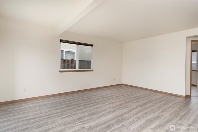 spare room featuring beamed ceiling, wood finished floors, and baseboards