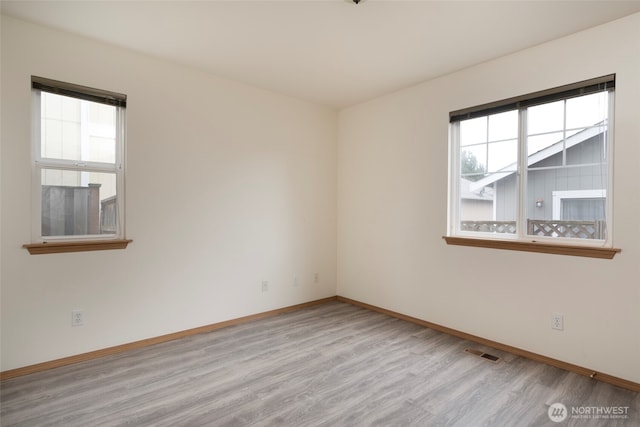 unfurnished room featuring visible vents, baseboards, and wood finished floors