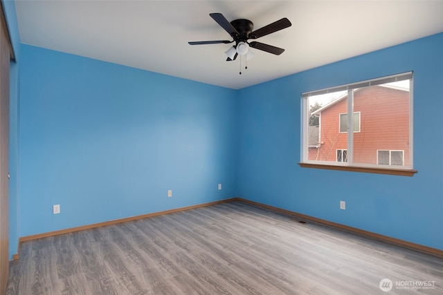 empty room featuring ceiling fan, baseboards, and wood finished floors