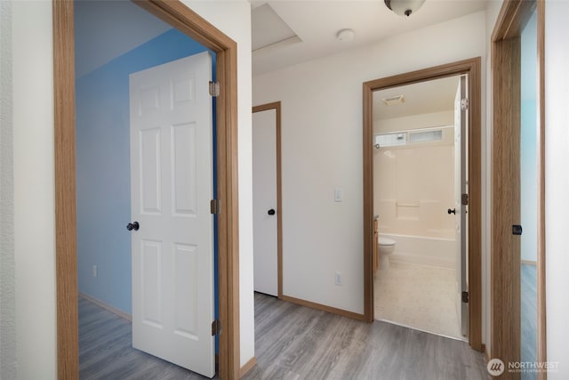 hallway featuring visible vents, wood finished floors, and baseboards