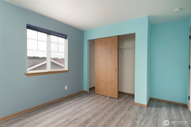 unfurnished bedroom with a closet, baseboards, and wood finished floors