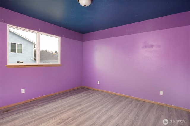 unfurnished room with baseboards and wood finished floors