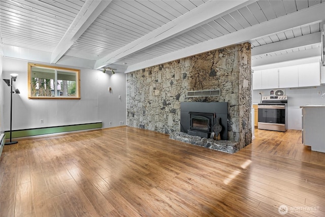 unfurnished living room featuring a sink, light wood-style floors, baseboard heating, and beamed ceiling