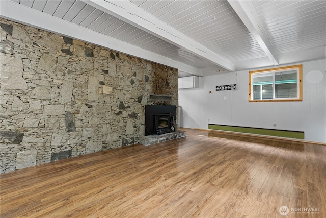 unfurnished living room with a baseboard heating unit, beamed ceiling, wood finished floors, and a wood stove