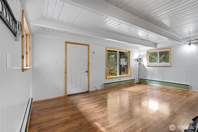 spare room with beam ceiling, a baseboard heating unit, and wood finished floors