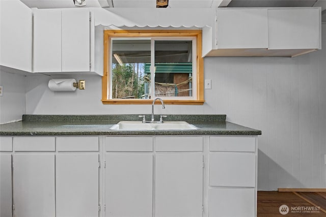 kitchen featuring a sink, dark countertops, and white cabinetry