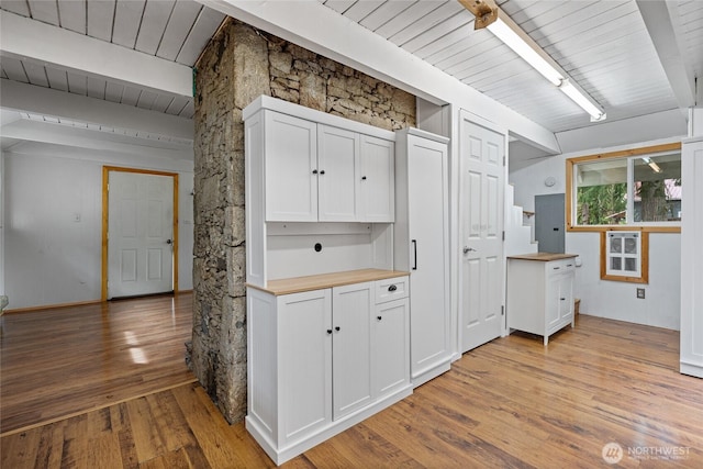 kitchen featuring light wood-type flooring, beamed ceiling, white cabinets, wooden ceiling, and wooden counters