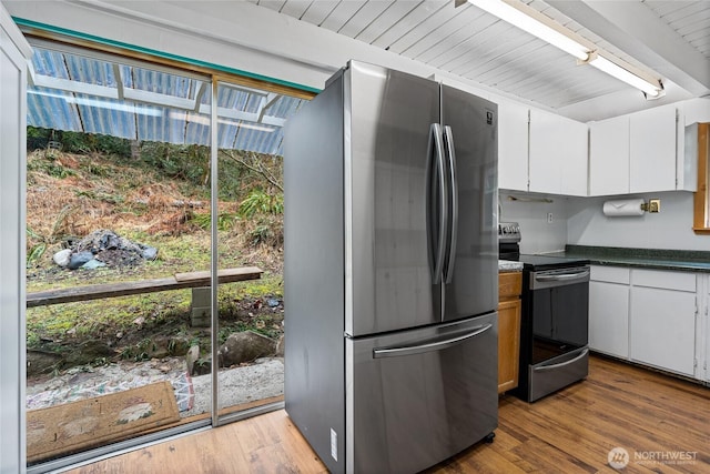 kitchen featuring wood finished floors, freestanding refrigerator, range with electric stovetop, dark countertops, and beamed ceiling