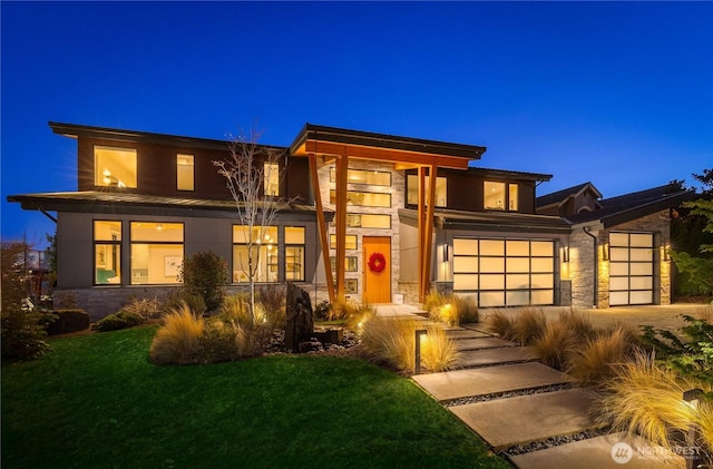 prairie-style house featuring a front lawn, stone siding, and driveway