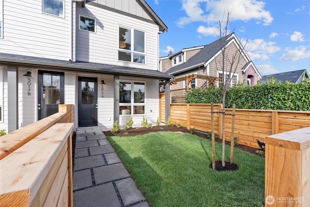 exterior space featuring board and batten siding, a front lawn, and fence