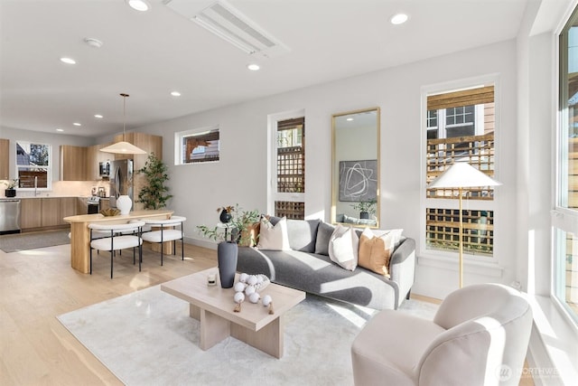 living room with recessed lighting, light wood-type flooring, and baseboards