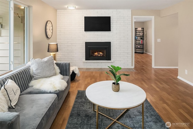 living room featuring a fireplace, baseboards, and wood finished floors