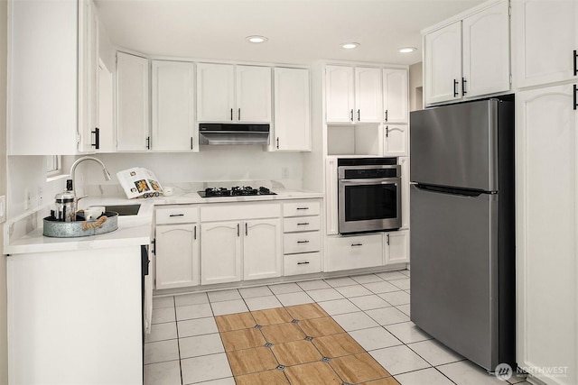 kitchen with under cabinet range hood, light tile patterned floors, appliances with stainless steel finishes, white cabinets, and a sink