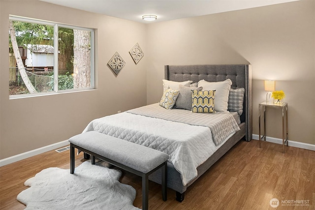 bedroom featuring visible vents, baseboards, and wood finished floors