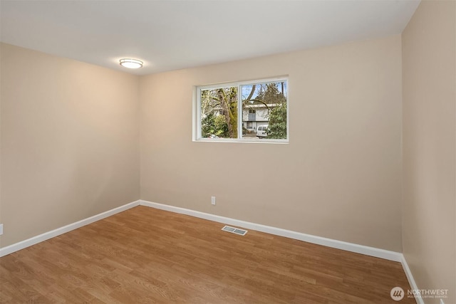 spare room with visible vents, baseboards, and wood finished floors