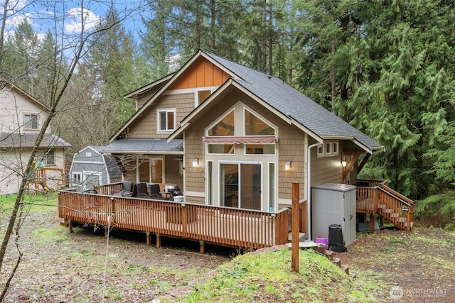 back of property with a wooden deck and a shingled roof