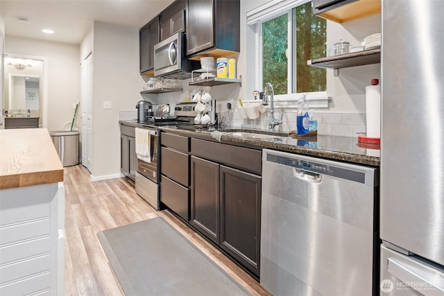 kitchen with light wood finished floors, a sink, appliances with stainless steel finishes, and open shelves